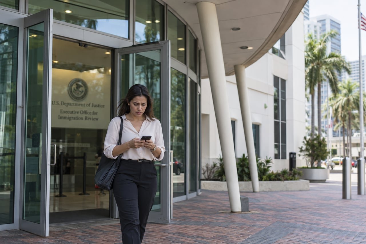 Mujer cubana sale preocupada de la corte de inmigración de Miami mirando su teléfono móvil
