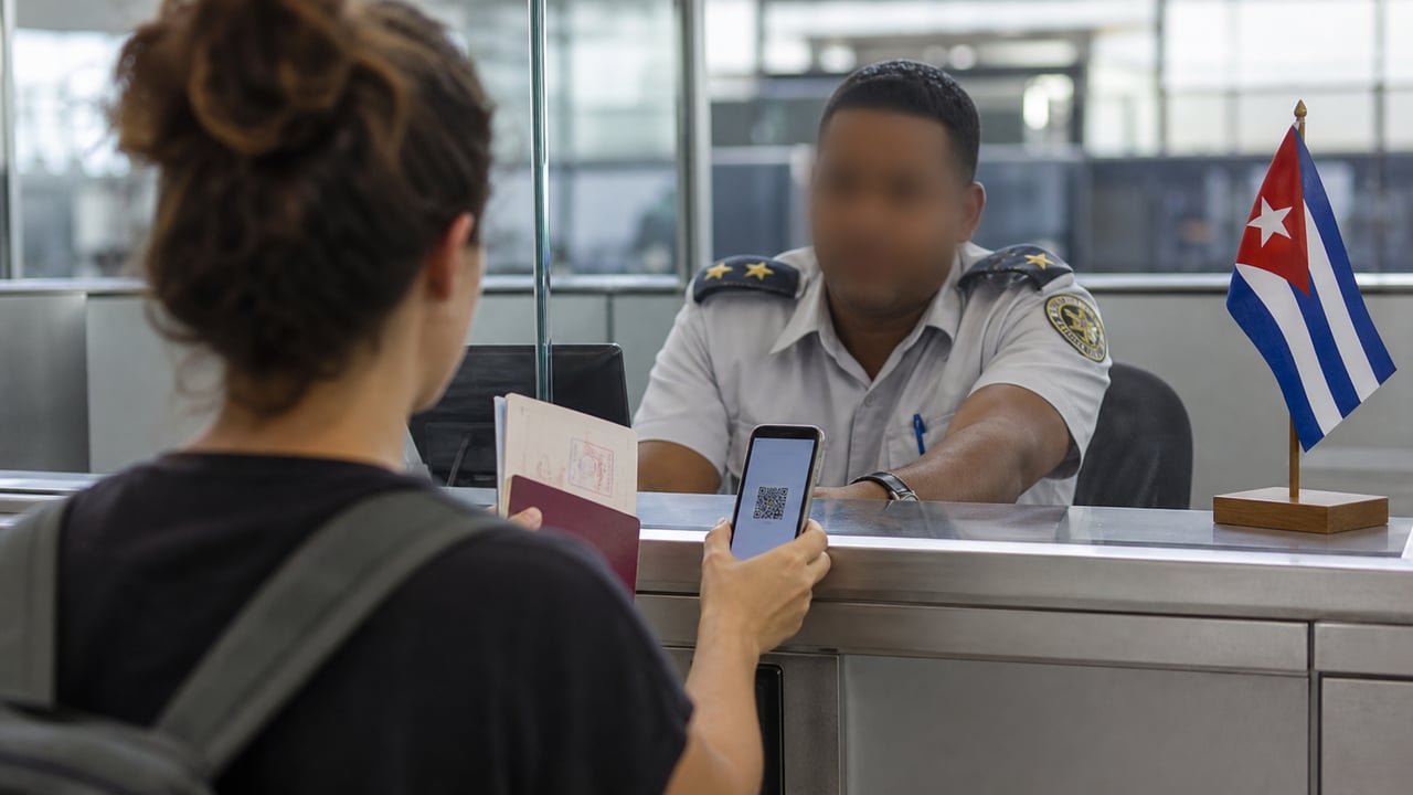 Viajero mostrando su código QR en el control de migración de un aeropuerto de Cuba, con la bandera cubana de fondo, ilustrando los requisitos de entrada a Cuba en 2026
